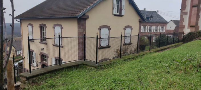 Pose d’une clôture en fer forgé sur un mur en grès à Oberbronn