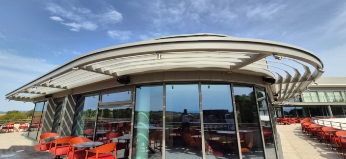 Fabrication et pose d’un brise-soleil sur mesure à l’Hôtel Royal Palace de Kirrwiller Brise-soleil courbe à lames au-dessus de la terrasse du restaurant de l'Hôtel Royal Palace, réalisé par Métallerie Willem